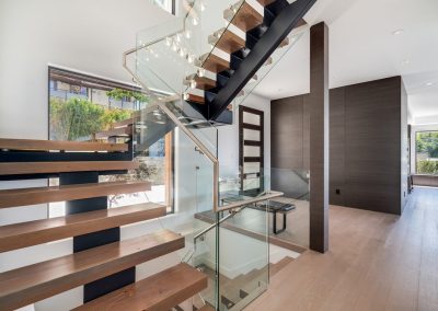 High end stairs with glass railings in a light filled home.