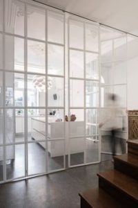 White bi-folding glass doors separating a kitchen from the rest of the house. 