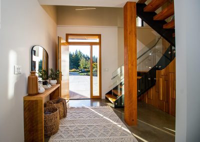 entryway with wood accents and glass railings on the stairs.