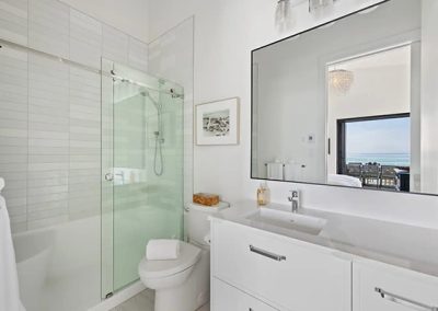 High end white bathroom with frameless sliding glass shower door.