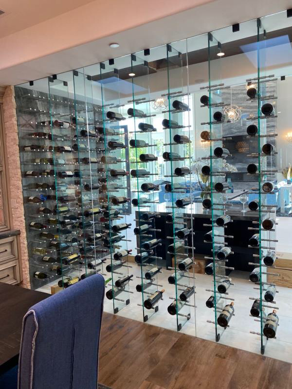 Large wall of wine bottles displayed on JRE hardware's wine pegs in front of a large mirrored wall.