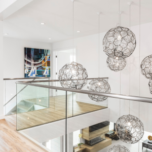 bright home with interesting hanging lights, glass railing divides the upstairs and downstairs